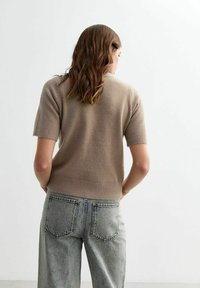 Korte mouwen trui in licht taupekleurige brei, met een ribgebreide zoom en manchetten, gecombineerd met hoge taille, vervaagde blauwe jeans.