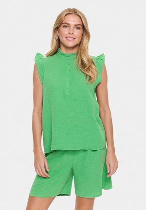 Completo coordinato verde con texture che presenta un top senza maniche con spalline arricciate e una fila di bottoni, abbinato a pantaloni corti coordinati.