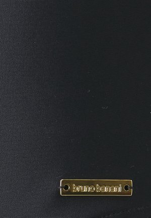Crni materijal s teksturiranom površinom, s zlatnom metalnom pločicom s logotipom na kojoj je u jednostavnom fontu ugravirano "bruno banani".