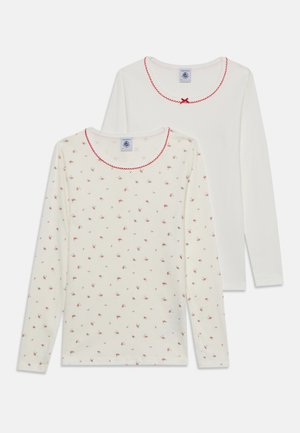 To hvide bluser til kvinder med lange ærmer, den ene ensfarvet og den anden med små røde blomsterprint, begge med rød bølget kant og lille sløjfe ved rund halsudskæring.
