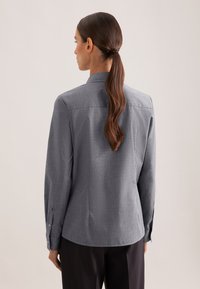 Camicia grigia con bottoni, collo e maniche lunghe, dal tessuto sottile e testurizzato. Presenta polsini classici con bottoni e una vestibilità comoda.