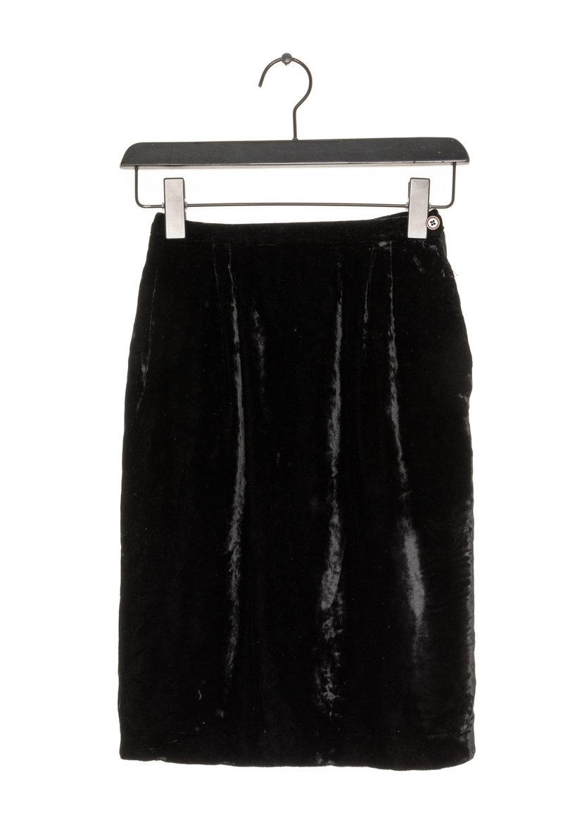 Svart sammetskjol hängande på en klädhanger. Har en slät yta med subtil lyster, knälång längd och minimalistisk design.