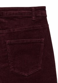 Tela de franela color burdeos con un bolsillo trasero y un lazo para cinturón que muestra una costura detallada en un par de pantalones.