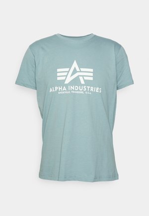 Jasnoniebieski bawełniany t-shirt z krótkimi rękawami, z białym logo i napisem "ALPHA INDUSTRIES" wyśrodkowanym na przodzie.