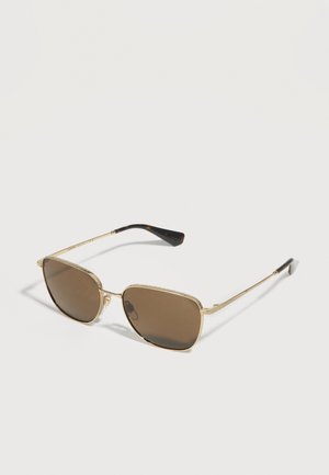 Lunettes de soleil avec monture en métal doré, verres rectangulaires teintés marron et branches fines noires sur fond blanc.