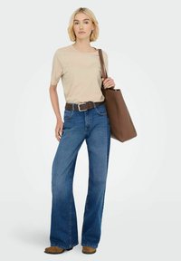 Beige shirt met korte mouwen, blauwe wijde jeans, bruine leren riem en bruine tote bag; lichte textuur met denimafwerking en minimalistische hardware.