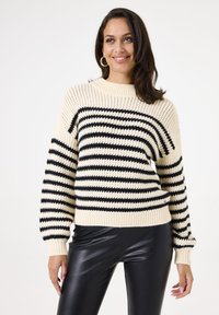 Knitted pullover in cream with black horizontal stripes, featuring a ribbed crew neckline and cuffs, textured fabric, and oversized fit.