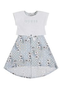 White cotton top with "GUESS LOS ANGELES" logo. Floral-patterned blue skirt with white trim and tie detail at waist.