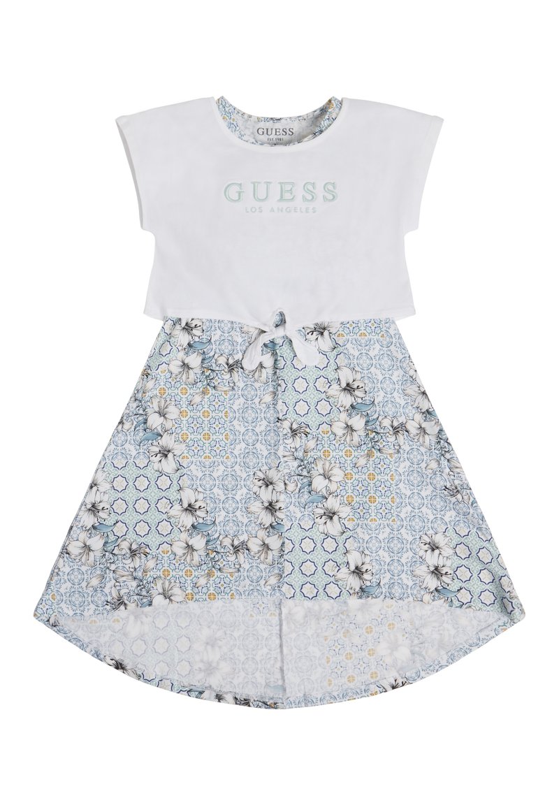 White cotton top with "GUESS LOS ANGELES" logo. Floral-patterned blue skirt with white trim and tie detail at waist.
