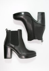Stivali ankle in pelle nera con pannelli elastici laterali testurizzati, un tacco a blocco spesso e una cerniera posteriore per la chiusura. Finitura liscia all'esterno.