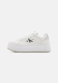 Sneaker platform bianchi con tomaia in pelle liscia, punta tonda e chiusura con lacci. Presentano un tacco metallizzato argento e un dettaglio con logo sul lato.