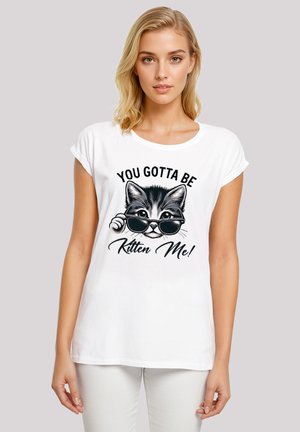 Weißes Baumwoll-T-Shirt mit umgeschlagenen Ärmeln, das ein Grafikdesign eines Katers in Sonnenbrille zeigt, mit dem Text "DU MUSST MICHVERARSCHE" in Schwarz.