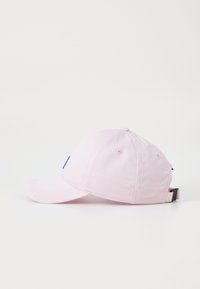 Rosa baseball cap med en buet skygge, solid stoff, justerbar stropp, med en blå logo på fronten. Myk tekstur og enkelt design.