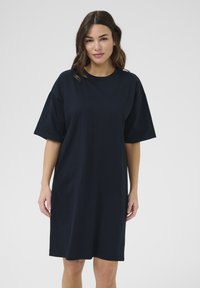 Navy t-shirt dress made of soft cotton, featuring short sleeves, a relaxed fit, and a straight hemline. Minimalist design with no patterns.
