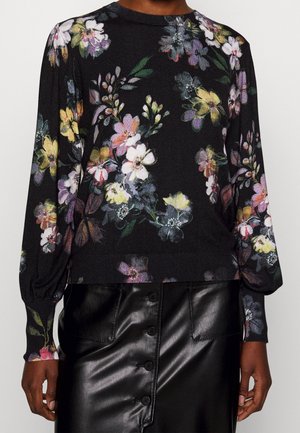 Pull noir à manches longues à fleurs multicolores, associé à une jupe en cuir noire boutonnée.
