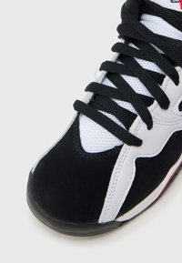 Αθλητικό παπούτσι σε μαύρο και άσπρο με ανάγλυφο ανώτερο μέρος από σουέντ, πάνελ από δίχτυ, χοντρές μαύρες κορδόνια και λαστιχένια σόλα. Διαθέτει χαρακτηριστικό σχέδιο.