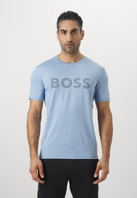 Camiseta de manga corta azul claro con un gran logo en gris oscuro que dice "BOSS" en el frontal. Fabricada con material suave y liviano.