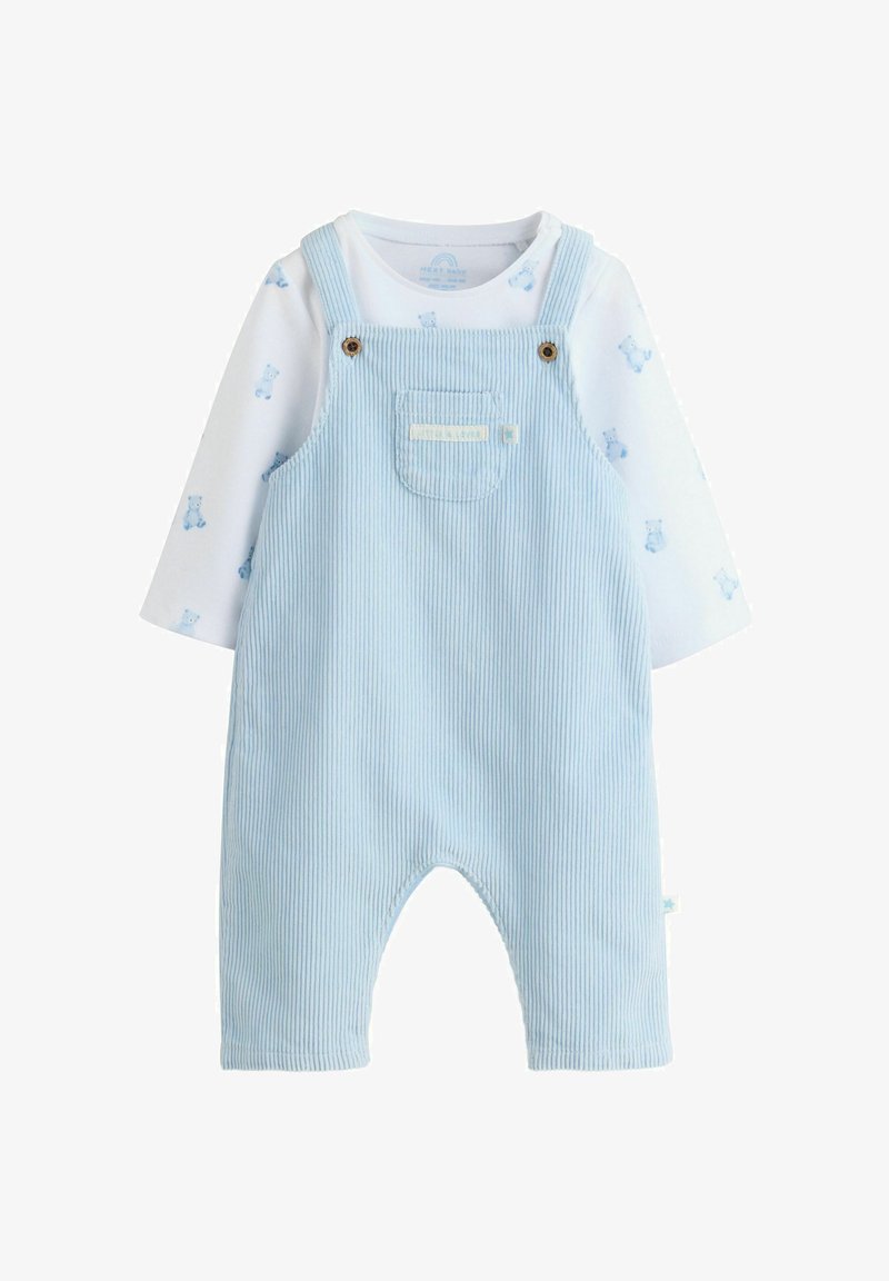 Hellblaue Corduroy-Latzhose mit einer Fronttasche, ergänzt durch Holzknopf-Details. Darunter ein weißes langärmliges Shirt mit Bärenmuster.