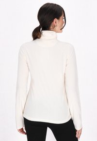 Cremefarvet langærmet turtleneck trøje, blødt stof, tætsiddende design og rundet kant, med et minimalistisk udseende uden synlige mønstre.