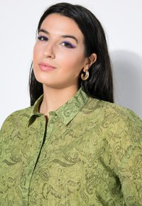 Groen overhemd met patroon en een button-down kraag, met ingewikkelde paisley ontwerpen en een licht gekreukte textuur.