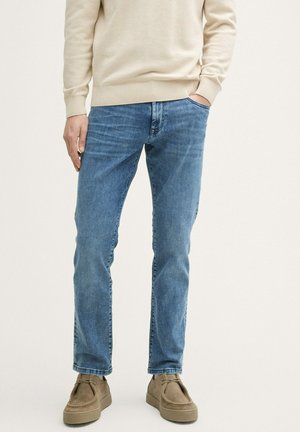 Jeans in denim azzurro chiaro con taglio dritto, dotati di tasche frontali e un sottile motivo sbiadito. Abbinati a scarpe slip-on in suede color testa di moro.
