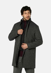 Grauer Herringbone-Mantel mit hohem Kragen und Knopfleiste, ausgestattet mit einer gesteppte Innenschicht, Seitentaschen und einer strukturierten Oberfläche.