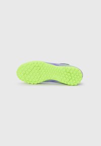 Semelle de chaussure dans un vert lime vibrant avec un motif texturé en nid d'abeille. Présente une partie supérieure violette et blanche pour un contraste de design supplémentaire.