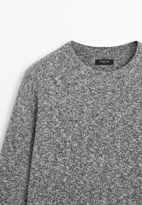 Maglione grigio lavorato a maglia con scollatura rotonda. Presenta un motivo testurizzato e polsini a costine. L'etichetta reca la scritta "Massimo Dutti". Tessuto morbido di peso medio.