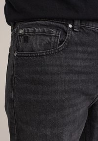 Zwarte denim jeans met een vervaagd uiterlijk, voorzien van een voorzak, metalen knoopsluiting en subtiele stikseldetails.