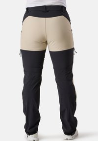 Herroutdoorbyxor med en beige övre del och svart underdel. Har dragkedjefickor och justerbara muddar. Tillverkade av mjukt, hållbart tyg.