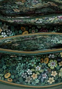 Floral-patterned fabric pouch in green tones, featuring multiple compartments with gold zipper accents. Textured floral design throughout.