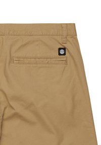 Pantaloni corti beige con una tasca posteriore dotata di un alette cucita e di una piccola etichetta con logo. Realizzati in un resistente tessuto di cotone con una finitura liscia.