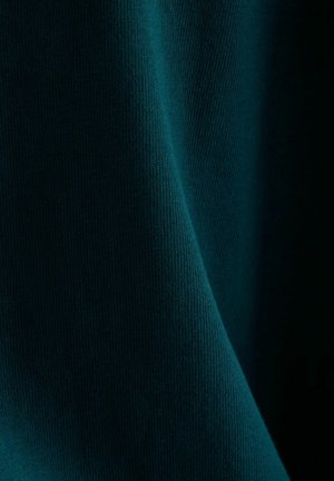 Tessuto verde petrolio scuro con texture a coste sottili, morbido piegato creando ombre delicate e riflessi.