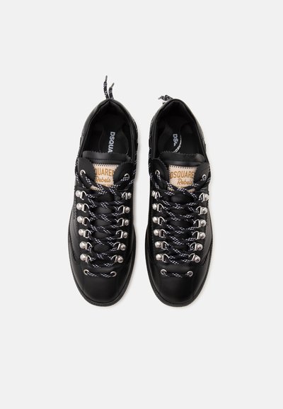 Ζευγάρι μαύρα δερμάτινα sneakers με κορδόνια με σχέδια και μεταλλικά παπούτσια, με κείμενο "DSQUARED2 Rebels" σε ετικέτες στη γλώσσα κρακεριού.