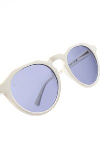 Bílé sluneční brýle s oválnými čočkami s lehce fialovým nádechem a výrazným, hranatým designem rámu. Ramena jsou elegantní a zakřivená.