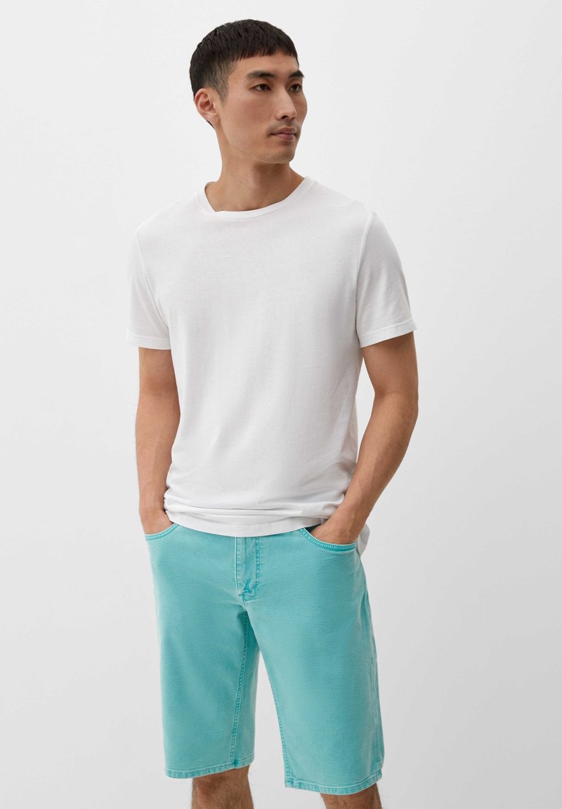 Biała koszulka z krótkim rękawem zestawiona z jasno turkusowymi szortami do kolan, posiadającymi boczne kieszenie i luźny krój. Miękka w dotyku.