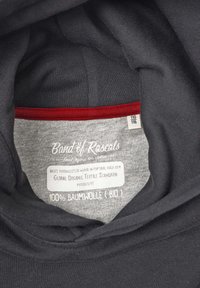 Hoodie i ekologisk bomull med en mörkgrå utsida, mjuk textur och en kontrasterande röd accent längs kragskyltet med skötselinstruktioner.