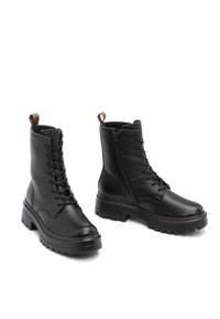 Bottines noires en cuir avec lacets, à semelles épaisses, fermetures éclairs latérales et languettes marron, présentées sur un fond blanc.