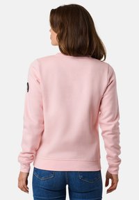 Felpa rosa chiaro realizzata in un morbido tessuto texturizzato, con scollatura rotonda, maniche lunghe e un piccolo logo nero sul braccio.