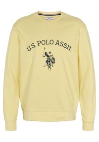 Žlutá bavlněná mikina s dlouhými rukávy, žebrovanými manžetami a spodním lemem, se černým logem U.S. Polo Assn. a grafikou jezdce na koni.