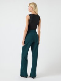 Zwarte mouwloze top gecombineerd met hooggewaisted teal wijde broek, met een gladde textuur en subtiele achterzakken.