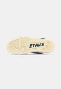 Shoe sole with a patterned, textured design in cream color featuring "ETNIES" logo. Material appears rubber with durable grip elements.