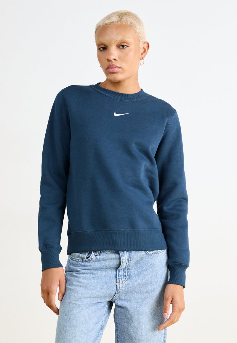 Mørkeblå hettegenser med rund hals, ribbede mansjetter og nederkant; har en liten hvit Nike-logo på brystet; laget av bomullsblandingsmateriale.