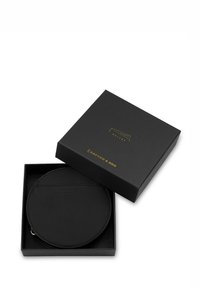 Portafoglio in pelle nera di forma circolare, ospitato in una scatola quadrata aperta nera con branding dorato sul coperchio. Texture liscia, design minimal.
