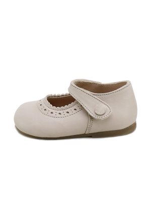 Zapato Mary Jane beige para niño pequeño con bordes ondulados, detalles perforados, una sola correa con botón y suela plana marrón.