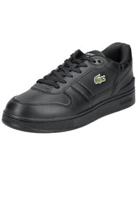 Black leather sneaker with lace-up closure, padded collar, textured rubber sole, and green crocodile logo accent on the side.