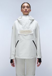 White, waterproof jacket with a hood, featuring a front pocket and black zippers. Includes a branded patch and elastic cuffs with thumb holes.