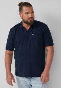 Granatowa koszulka polo z teksturowanej tkaniny, z krótkim kołnierzykiem, kieszenią z przodu i małym logo na piersi.