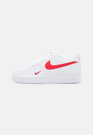 Hvid lavtop sneaker med røde Nike swoosh-logoer på siden og ved snørebånd, hvid sål med tekstureret greb og perforeret tåområde.