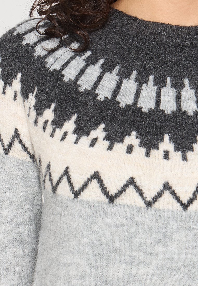 Szary sweter z dzianiny z geometrycznym wzorem w czerni i bieli. Okrągły dekolt, teksturowane wykończenie oraz kontrastowy zygzakowaty detal na końcu.